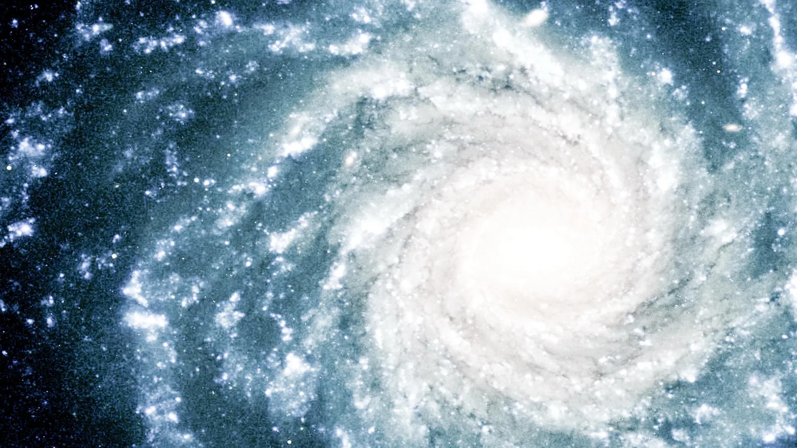 Spiralgalaxie im Weltall, von einem hellen Kern aus winden sich bläulich-weiße Arme mit Sternenhaufen nach außen, dunkler Hintergrund mit verstreuten Sternen.