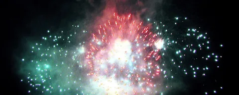 Feuerwerk mit roten und grünen Funken vor schwarzem Nachthimmel