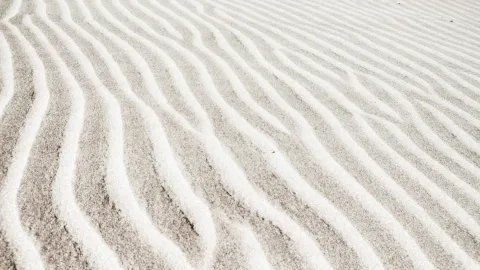 Helle Sandrippel mit geschwungenen Linien in Schrägsicht, dazwischen graubeige Sandflächen.
