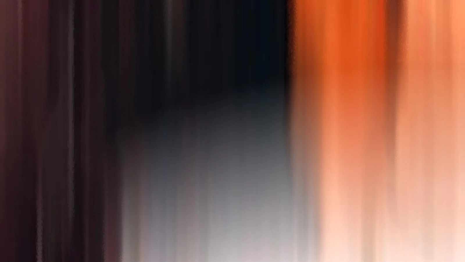 Stark verwischte, vertikale Streifen in Orange, Schwarz und Grau, links dunkelrot, rechts helles Orange.