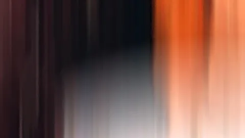 Stark verwischte, vertikale Streifen in Orange, Schwarz und Grau, links dunkelrot, rechts helles Orange.