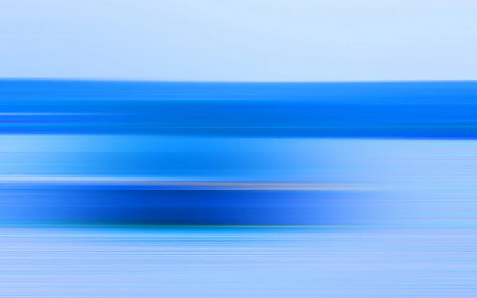 Horizontal verwischte Streifen in Blau- und Hellblautönen, oben ein heller Himmelsbereich, darunter dunklere blaue Bänder.