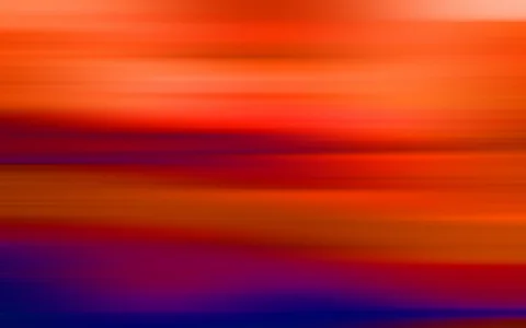Unscharfe horizontale Schlieren in Orange, Rot und Violett, unten in dunklem Blau, wie durch eine Bewegungsunschärfe erzeugt.