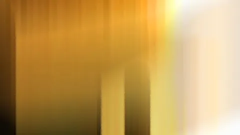 Unscharfe vertikale Streifen in Gold und Ocker, nach rechts hin in helles Creme verblassend, mit zwei dunkleren Feldern in der Bildmitte.