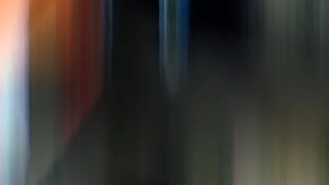 Abstrakte, vertikal verwischte Farbstreifen in Orange, Rot, Dunkelgrau und Blau auf dunklem Grund.