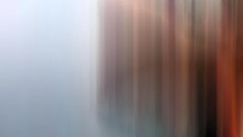 Vertikal verwischte Streifen: links ein kühles Grau-Blau, rechts warme Braun- und Orangetöne.