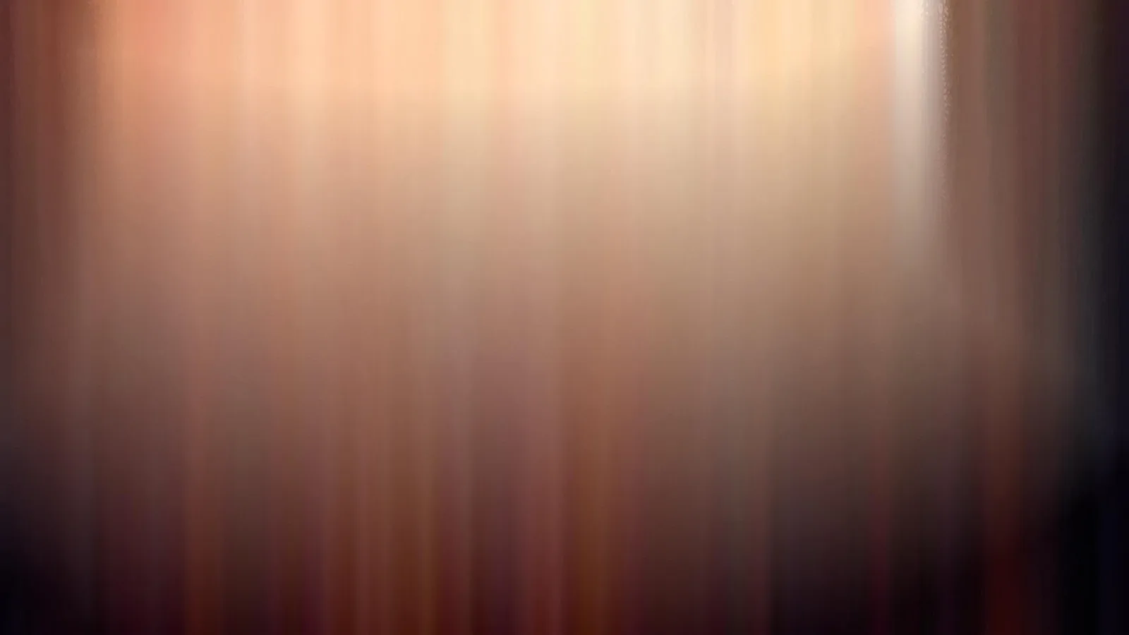 Unscharfe senkrechte Streifen in Orange und Braun, das hellste Licht oben, zu den Rändern hin dunkler werdend.