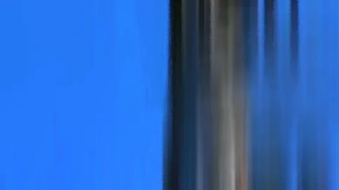 Links leuchtend blauer Himmel, rechts verwischte dunkle und graue vertikale Streifen