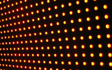 Raster aus leuchtend orangefarbenen Punkten auf schwarzem Hintergrund
