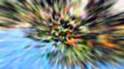 Stark verwischte Aufnahme mit radialem Bewegungsunschärfe-Effekt: Von einem Zentrum aus strahlen bunte Streifen in Grün, Orange, Lila und Weiß nach außen, unten links dominiert helles Blau.