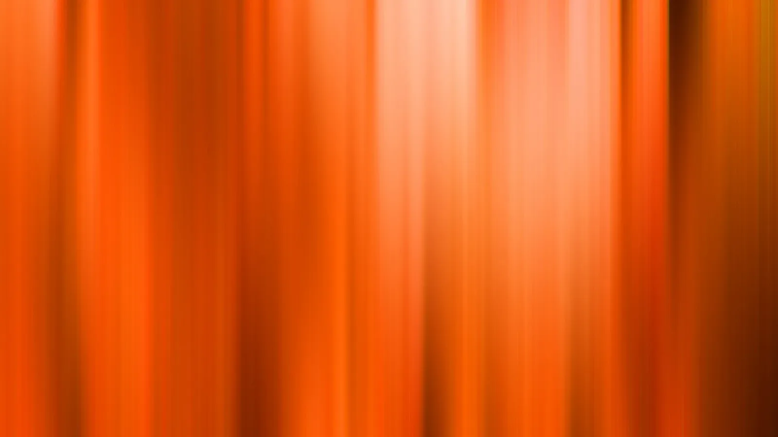 Verwischte vertikale Streifen in Orange und Rotorange, heller Lichtschein in der Bildmitte