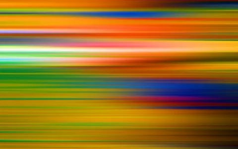 Abstrakte horizontale Streifen in Orange, Gelb, Grün und Blau, die wie verwischte Lichtspuren von links nach rechts verlaufen.