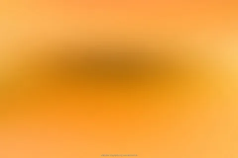 Unscharfer Farbverlauf in Orange und Gelb mit einem dunkleren, bräunlichen Bereich in der Bildmitte.