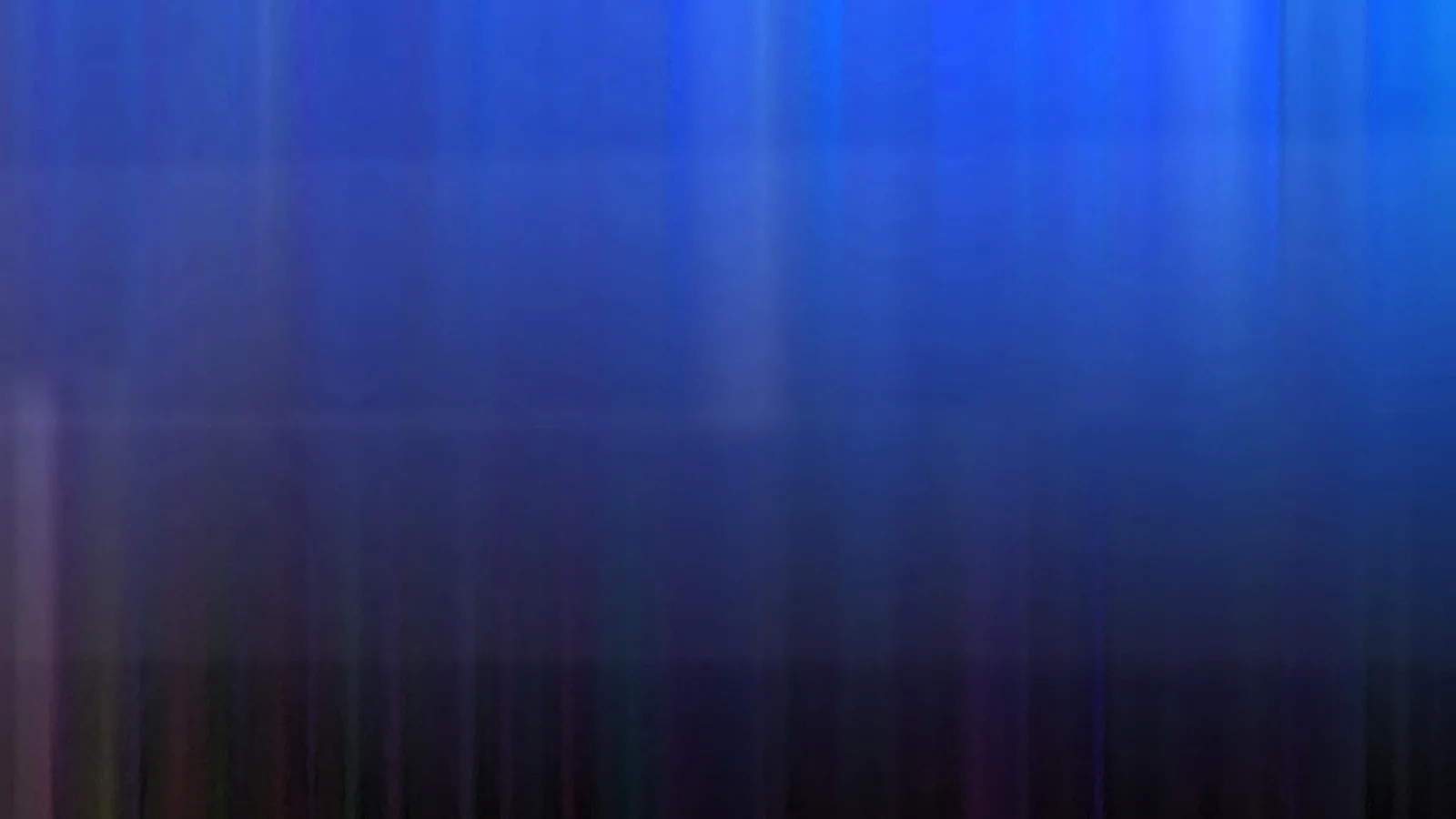 Abstrakte, senkrecht verwischte Streifen, oben in Blau, unten in dunkles Violett übergehend.