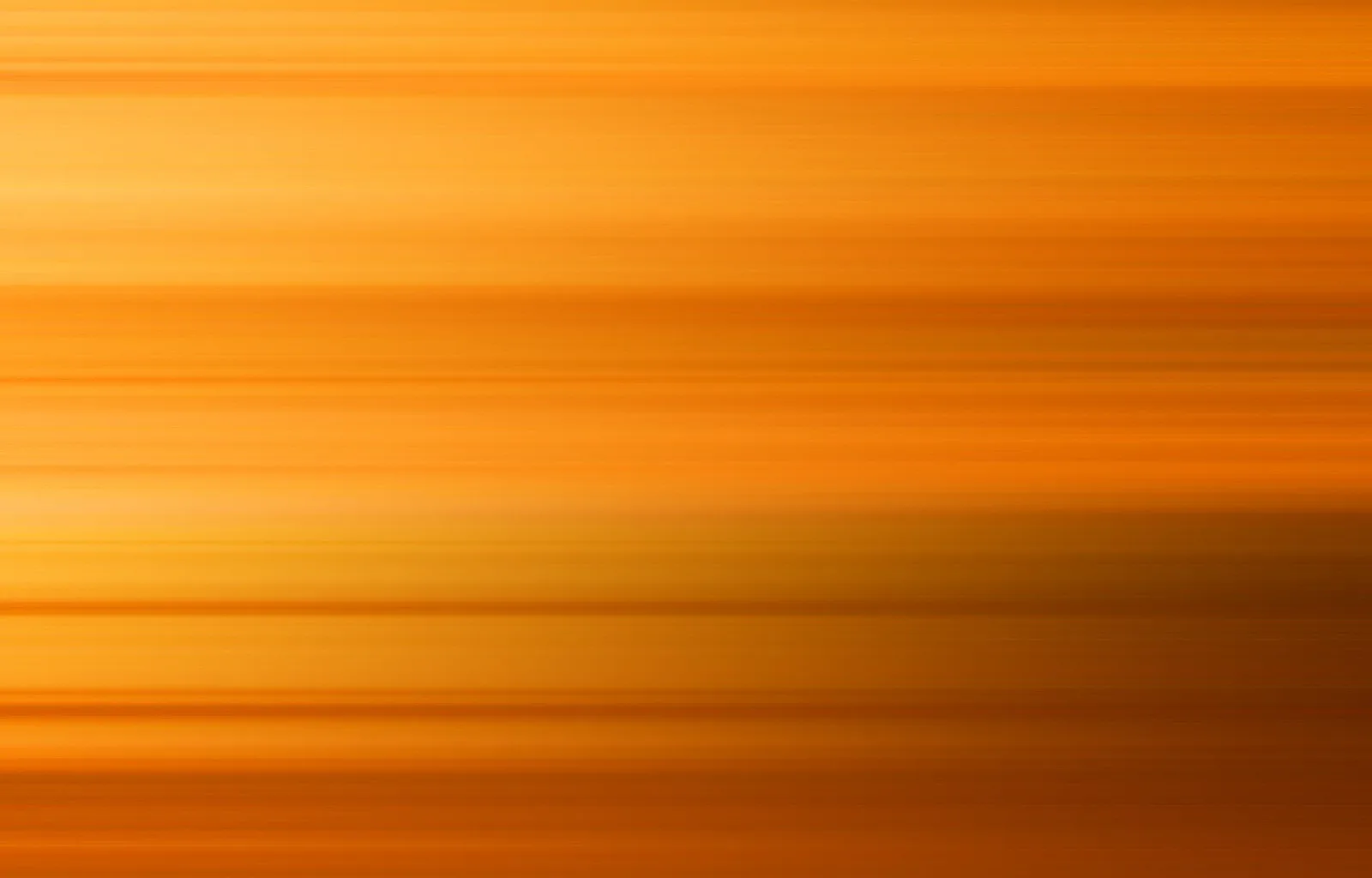Abstrakte Fläche aus horizontalen, verwischten Streifen in Orange- und Gelbtönen, nach oben heller, unten dunkler werdend.
