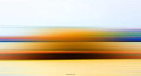 Horizontal verwischte Farbstreifen in Blau, Orange und Gelb, oben heller, leicht bewölkter Himmelsbereich.