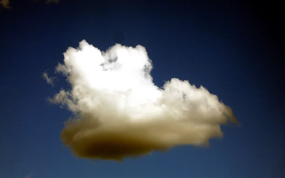 Eine weiß leuchtende Haufenwolke mit grauem Schatten an der Unterseite vor dunkelblauem Himmel.