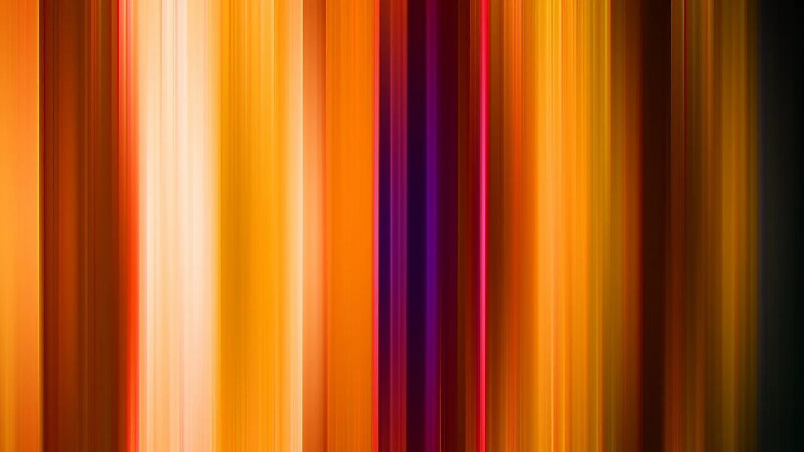 Vertikale, verwischte Streifen in Orange, Gelb, Weiß und Violett auf dunklem Grund, wie eine Bewegungsunschärfe.