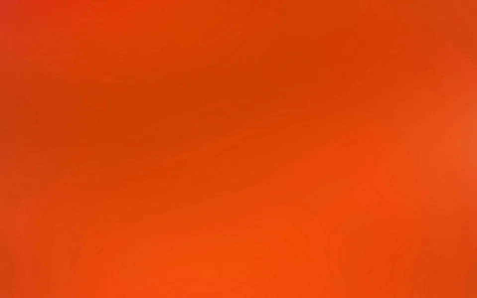 Fast vollflächiger Farbverlauf von tiefem Rot oben links zu leuchtendem Orange unten rechts, mit einem helleren Lichtfleck am rechten Rand.