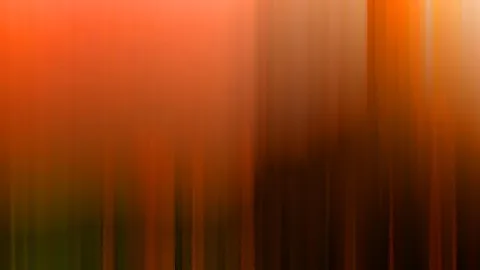 Abstrakte, vertikal verwischte Aufnahme mit Orange und Rot links und dunklem Braun bis Schwarz rechts, unten grünlich dunkel.