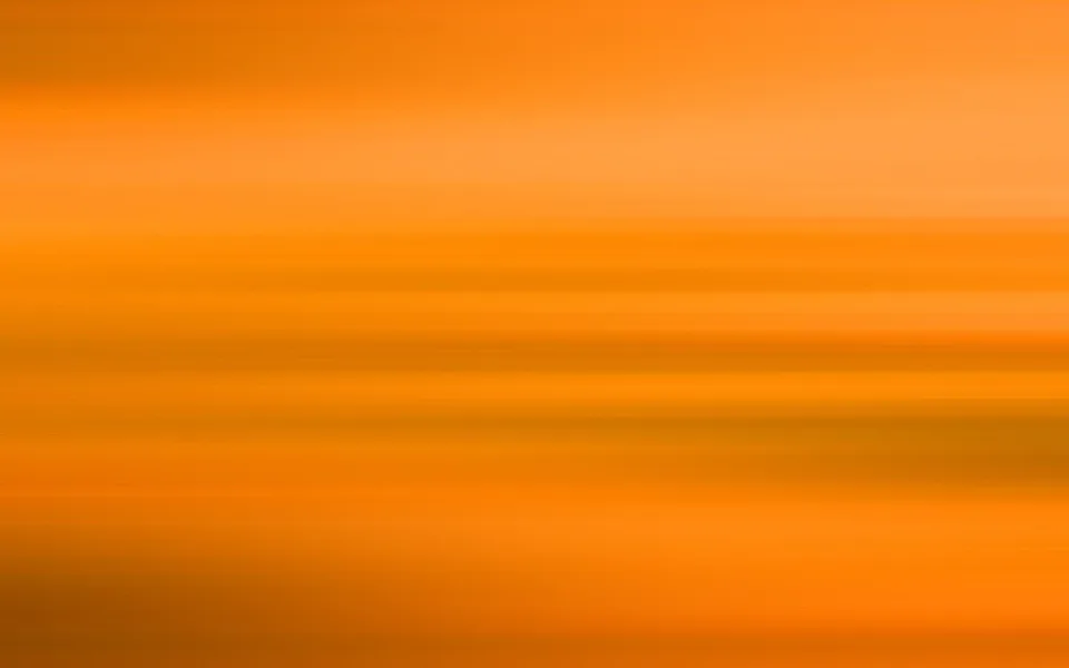 Abstrakte, horizontal verwischte Streifen in Orange- und Gelbtönen, von hell oben bis dunkler unten.
